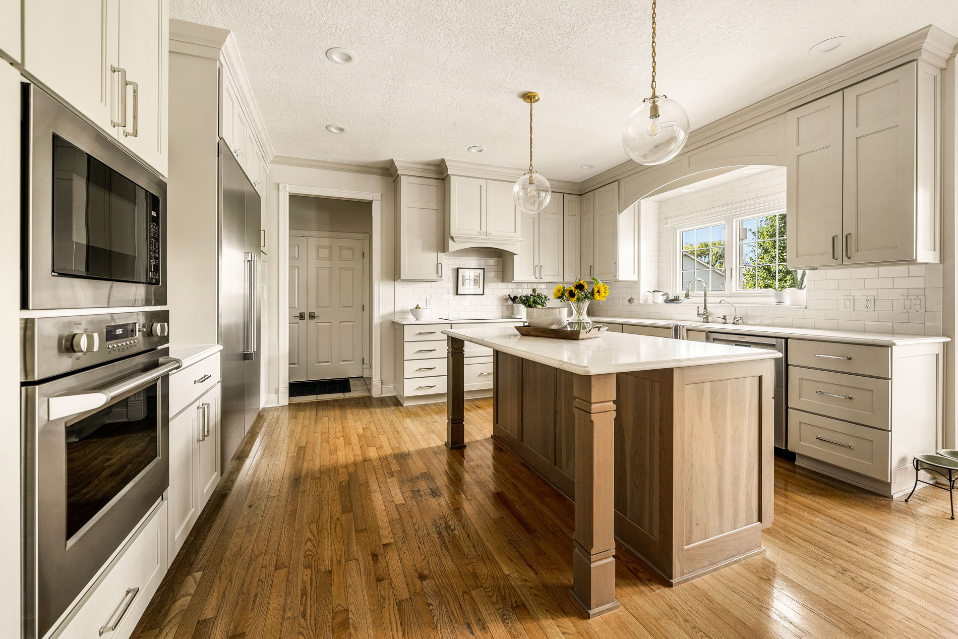 Home Remodeling Des Moines - Beautiful white and gray kitchen with natural wood floor, featuring a quartz top island.